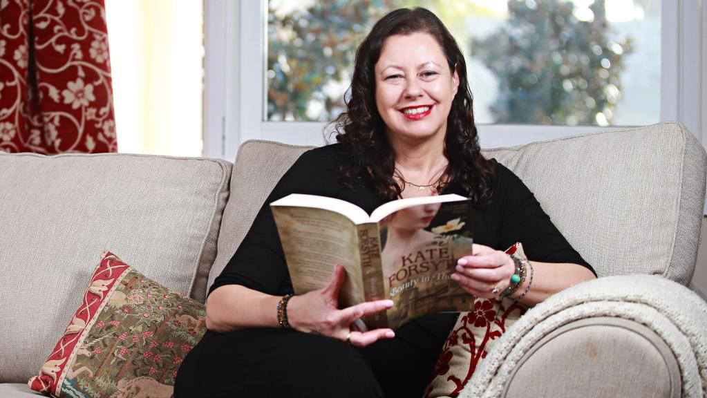 Kate Forsyth on a sofa reading one of her novels.