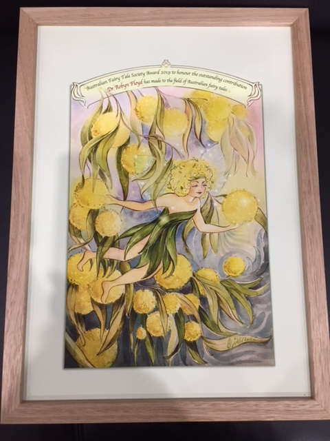 Framed picture of a wattle fairy with wattle-flower hair in a wattle bush, with a title awarding the 2019 AFTS Award to Dr Robyn Floyd.