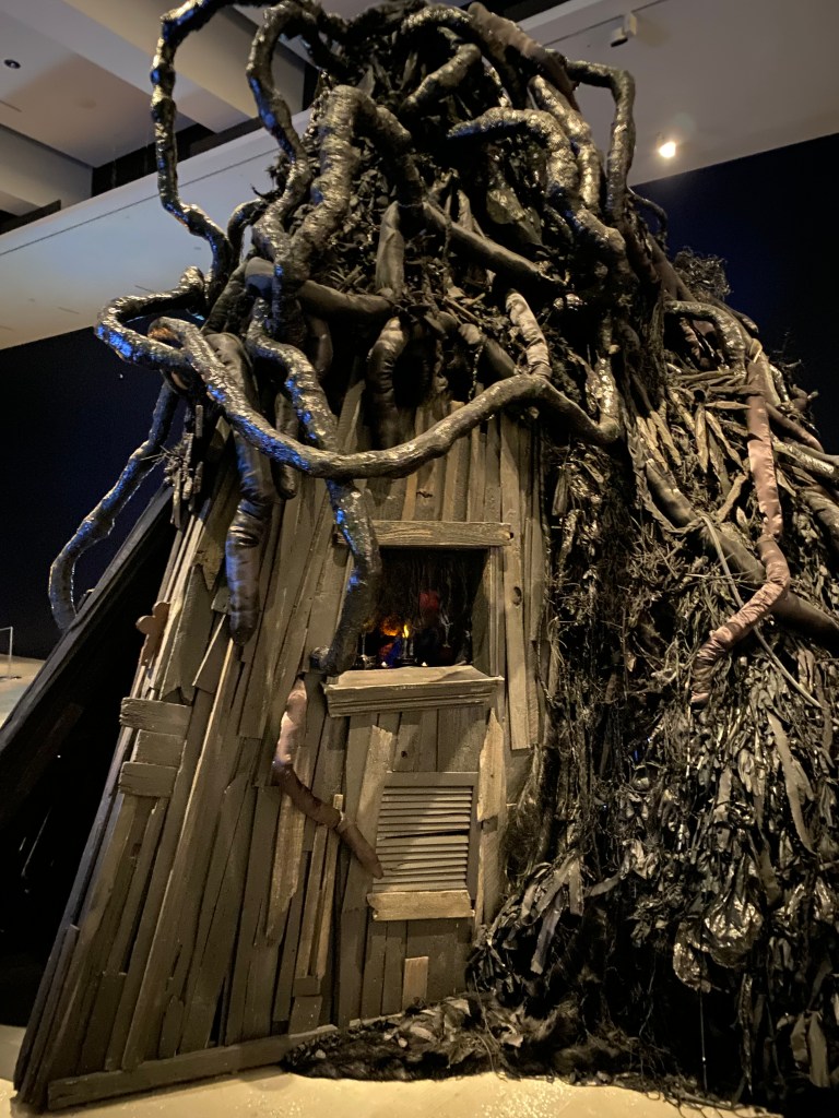 Tree trunk and branches growing around wooden hut at GOMA